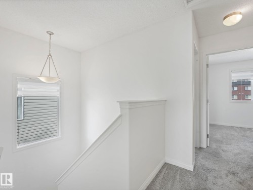 The property features a staircase with white handrails and walls, complemented by grey carpeting - 675 Mcallister Loop, Edmonton, AB - Indoor Photo Showing Other Room