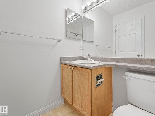 The bathroom features a vanity with a light wood cabinet, a white sink, and a gray countertop - 675 Mcallister Loop, Edmonton, AB - Indoor Photo Showing Bathroom