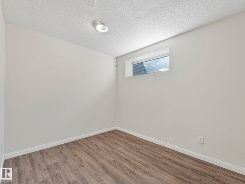 This room features light-colored walls, wood-look flooring, and a window providing natural light - 675 Mcallister Loop, Edmonton, AB - Indoor Photo Showing Other Room