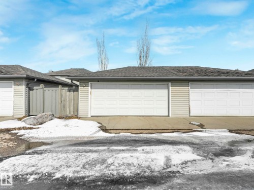 The property features a double garage with white garage doors and light-colored siding - 675 Mcallister Loop, Edmonton, AB - Outdoor