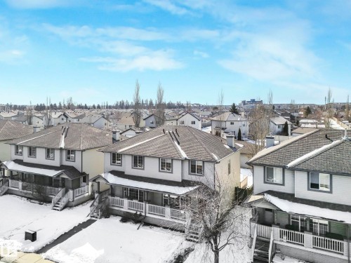 The property is situated within a vibrant community, featuring a residential street lined with houses, each featuring a pitched roof and a front porch - 675 Mcallister Loop, Edmonton, AB - Outdoor With Deck Patio Veranda