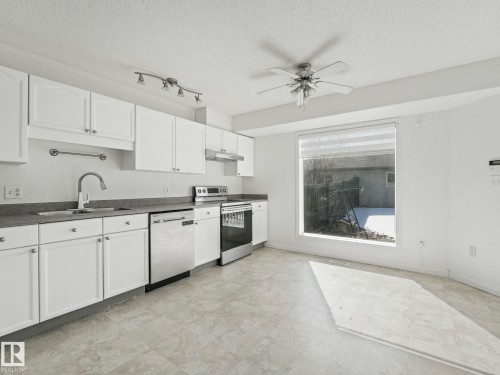 The kitchen features white cabinetry, stainless steel appliances, and a window with a view to the outdoor space - 675 Mcallister Loop, Edmonton, AB - Indoor Photo Showing Kitchen