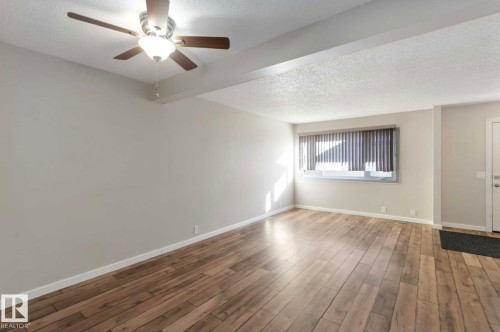 Spacious room featuring wood flooring, a window with blinds, and a ceiling fan - 8 14511 52 Street, Edmonton, AB - Indoor Photo Showing Other Room