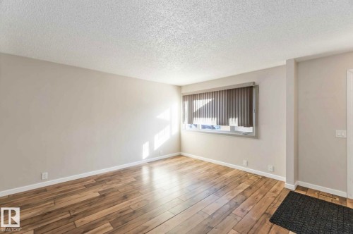 This room features hardwood flooring and a window with blinds, allowing for natural light - 8 14511 52 Street, Edmonton, AB - Indoor Photo Showing Other Room