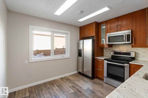 The kitchen features stainless steel appliances, a tile backsplash, and light-colored countertops - 8 14511 52 Street, Edmonton, AB - Indoor Photo Showing Kitchen