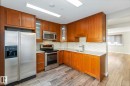 The kitchen features wood cabinetry, stainless steel appliances, and light-colored countertops with a tiled backsplash - 8 14511 52 Street, Edmonton, AB  - Indoor Photo Showing Kitchen 