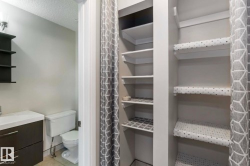 The bathroom features a vanity with a white countertop and a white toilet - 8 14511 52 Street, Edmonton, AB - Indoor With Storage