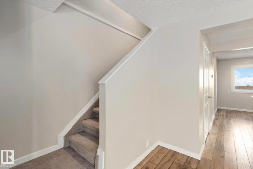 The property features a staircase with carpeted treads and a light-colored banister - 8 14511 52 Street, Edmonton, AB - Indoor Photo Showing Other Room