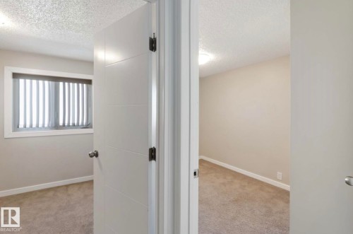 The property features rooms with neutral-toned walls, textured ceilings, and light-colored carpet flooring - 8 14511 52 Street, Edmonton, AB - Indoor Photo Showing Other Room