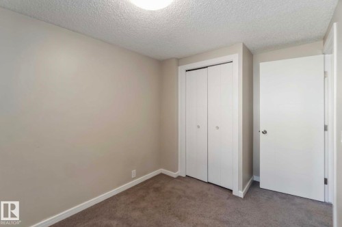 Bedroom with plush carpet, a built-in closet with bi-fold doors, and a neutral wall color - 8 14511 52 Street, Edmonton, AB - Indoor Photo Showing Other Room