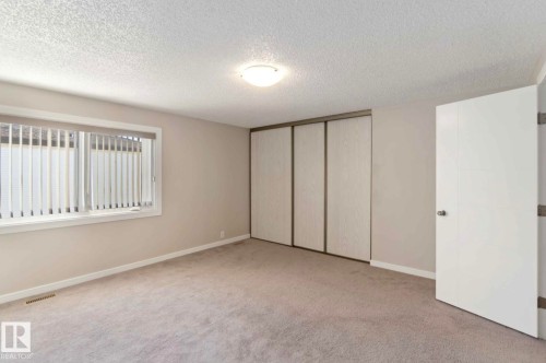 This room features neutral-toned walls, a window with vertical blinds, and a light-colored carpet - 8 14511 52 Street, Edmonton, AB - Indoor Photo Showing Other Room