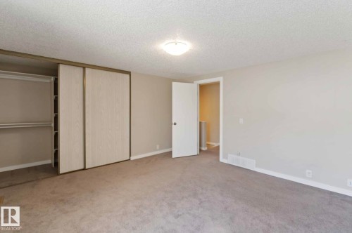 This room features neutral-toned carpeting, light-colored walls, and a ceiling light fixture - 8 14511 52 Street, Edmonton, AB - Indoor Photo Showing Other Room
