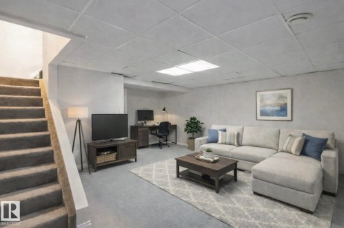 This room features light gray carpeting, a drop ceiling with recessed lighting, and a neutral wall color - 8 14511 52 Street, Edmonton, AB - Indoor