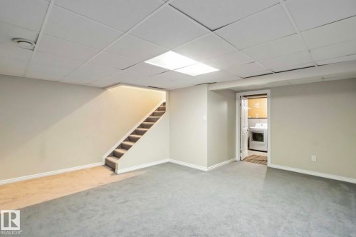 The property features an expansive room with light-colored walls and carpeted flooring - 8 14511 52 Street, Edmonton, AB - Indoor