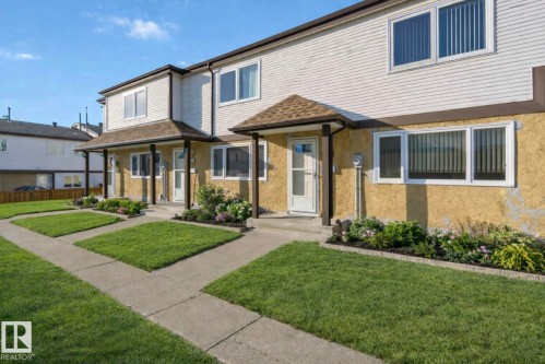 The property features a well-maintained lawn with concrete pathways and landscaped garden beds at the front - 8 14511 52 Street, Edmonton, AB - Outdoor With Facade