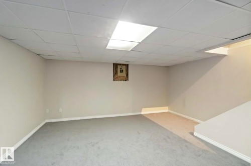 Spacious room with light-colored walls, grey carpet, and a drop ceiling with integrated lighting - 8 14511 52 Street, Edmonton, AB - Indoor