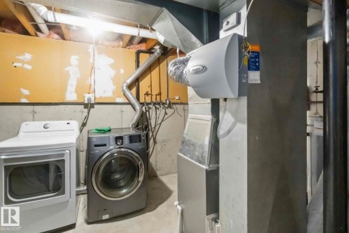 Laundry area featuring a front-loading washing machine, a dryer, and exposed ductwork - 8 14511 52 Street, Edmonton, AB - Indoor Photo Showing Laundry Room
