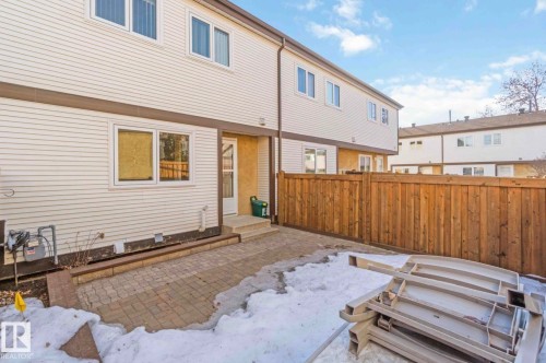 The property features a private patio area with paving stones, bordered by a wooden privacy fence - 8 14511 52 Street, Edmonton, AB - Outdoor With Exterior