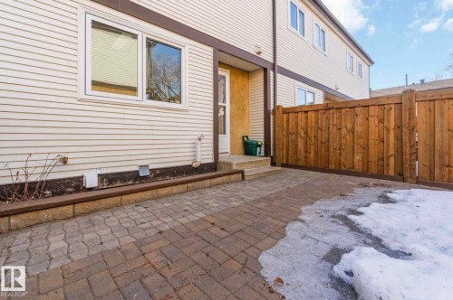 This property features a paved patio area with a wooden fence - 8 14511 52 Street, Edmonton, AB - Outdoor With Exterior