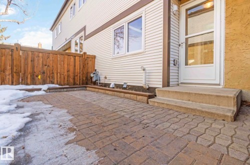 The property features a private patio area with paver stones, accessible via a door with a storm door - 8 14511 52 Street, Edmonton, AB - Outdoor With Exterior