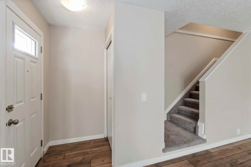 The property features a welcoming entryway with wood-style flooring and a white paneled door with an upper window - 8 14511 52 Street, Edmonton, AB - Indoor Photo Showing Other Room
