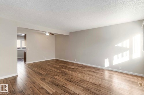 Spacious living area featuring hardwood flooring, light neutral-toned walls, and a ceiling fan - 8 14511 52 Street, Edmonton, AB - Indoor Photo Showing Other Room