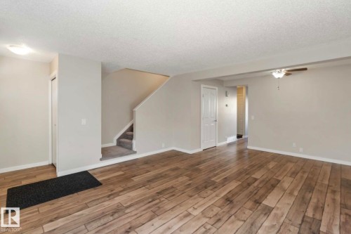 The property features durable wood-style flooring, a staircase with carpeting, and light-colored walls throughout - 8 14511 52 Street, Edmonton, AB - Indoor Photo Showing Other Room
