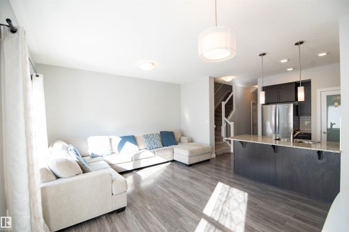 The open concept living area features light-toned flooring, a kitchen island with a granite countertop, and stainless steel appliances - 1793 Keene Crescent, Edmonton, AB - Indoor