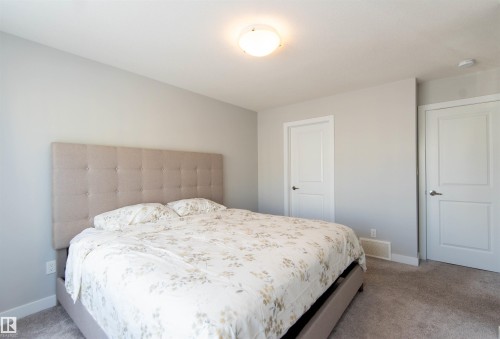 This bedroom features light gray walls, a ceiling light fixture, and two white panel doors - 1793 Keene Crescent, Edmonton, AB - Indoor Photo Showing Bedroom