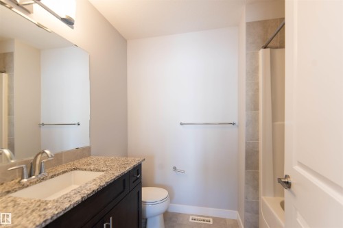 The bathroom features a vanity with a granite countertop, a toilet, and a shower with tiled walls - 1793 Keene Crescent, Edmonton, AB - Indoor Photo Showing Bathroom