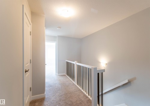 The property features a hallway with light-colored carpet flooring and light grey walls - 1793 Keene Crescent, Edmonton, AB - Indoor Photo Showing Other Room