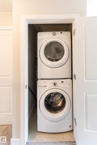 Dedicated laundry closet featuring a stacked washer and dryer, with tiled flooring - 1793 Keene Crescent, Edmonton, AB - Indoor Photo Showing Laundry Room
