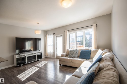 Living area featuring dark wood-style flooring, a large window, and a glass-paneled door, providing natural light - 1793 Keene Crescent, Edmonton, AB - Indoor Photo Showing Living Room