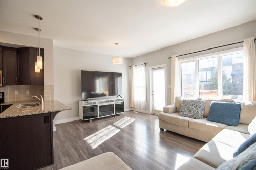 Open concept living area with wood flooring and natural light from large windows and a glass door - 1793 Keene Crescent, Edmonton, AB - Indoor Photo Showing Living Room