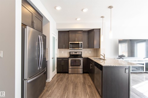 This kitchen features stainless steel appliances, dark cabinetry, light countertops, and recessed lighting - 1793 Keene Crescent, Edmonton, AB - Indoor Photo Showing Kitchen With Double Sink With Upgraded Kitchen