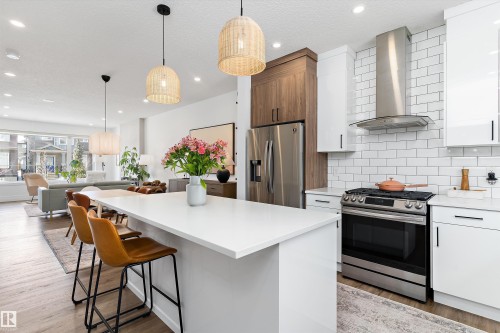 The kitchen features an expansive island, stainless steel appliances, and a white subway tile backsplash - 1305 Enright Landing, Edmonton, AB - Indoor Photo Showing Kitchen With Stainless Steel Kitchen With Upgraded Kitchen