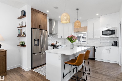 Modern kitchen featuring a white island with a quartz countertop, stainless steel appliances, white subway tile backsplash, and wood-look flooring - 1305 Enright Landing, Edmonton, AB - Indoor Photo Showing Kitchen With Stainless Steel Kitchen With Upgraded Kitchen