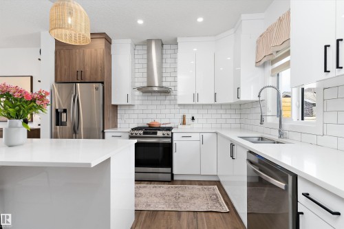 Modern kitchen featuring white cabinetry, subway tile backsplash, stainless steel appliances, and a central island with a white countertop - 1305 Enright Landing, Edmonton, AB - Indoor Photo Showing Kitchen With Stainless Steel Kitchen With Double Sink With Upgraded Kitchen