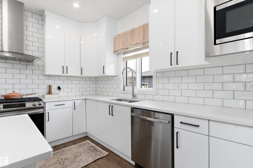The kitchen features white cabinetry, white subway tile backsplash, stainless steel appliances, and a window - 1305 Enright Landing, Edmonton, AB - Indoor Photo Showing Kitchen With Stainless Steel Kitchen With Double Sink With Upgraded Kitchen