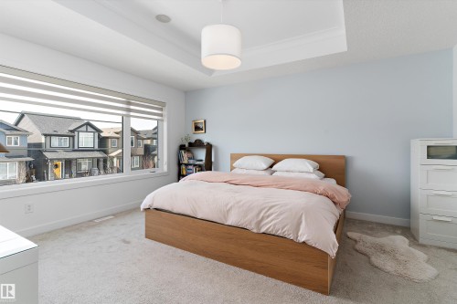 This room features light blue walls, a tray ceiling, and light-colored carpeting - 1305 Enright Landing, Edmonton, AB - Indoor Photo Showing Bedroom