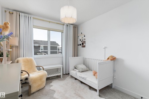This room features a window with white curtains, a white ceiling light fixture, and light-colored carpet - 1305 Enright Landing, Edmonton, AB - Indoor Photo Showing Bedroom