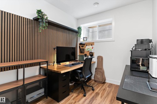 The room features wood-look flooring, a window, and a decorative slatted wood wall panel - 1305 Enright Landing, Edmonton, AB - Indoor Photo Showing Office