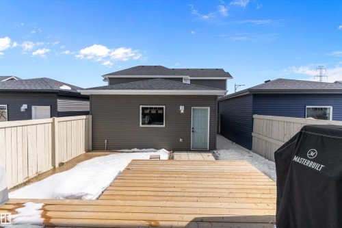 The property features a wooden deck, a wooden fence, and a detached building with dark gray siding and a light blue door - 1305 Enright Landing, Edmonton, AB - Outdoor With Deck Patio Veranda With Exterior