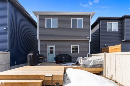 The property features a spacious wooden deck with steps, leading to a light blue back door - 1305 Enright Landing, Edmonton, AB - Outdoor With Exterior