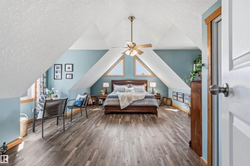 This bright room features sloped white ceilings and light blue walls, complemented by wood flooring - 17 Sunset Harbour, Rural Wetaskiwin County, AB - Indoor Photo Showing Other Room