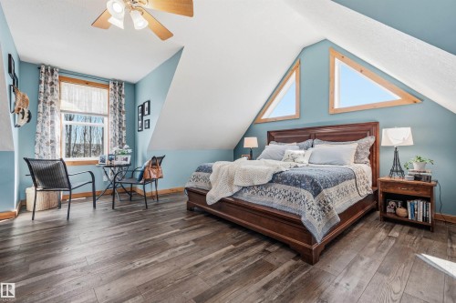 Spacious room featuring wood-look flooring, sloped ceilings, and triangular windows providing natural light - 17 Sunset Harbour, Rural Wetaskiwin County, AB - Indoor Photo Showing Bedroom