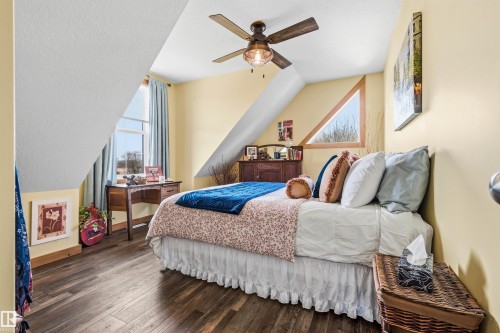 This room features vaulted ceilings, rich wood flooring, and a ceiling fan with integrated lighting - 17 Sunset Harbour, Rural Wetaskiwin County, AB - Indoor Photo Showing Bedroom