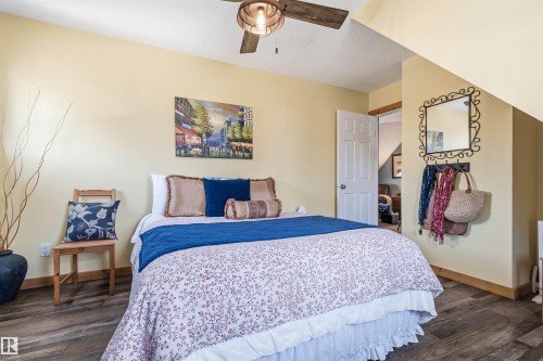 This room features warm-toned walls, a ceiling fan with a light fixture, and wood-look flooring - 17 Sunset Harbour, Rural Wetaskiwin County, AB - Indoor Photo Showing Bedroom