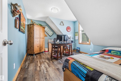 This room features sloped ceilings, durable plank flooring, and a window with a wood frame - 17 Sunset Harbour, Rural Wetaskiwin County, AB - Indoor Photo Showing Bedroom