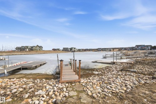 The property offers direct access to the water with a private wooden dock, set against a backdrop of a clear blue sky - 17 Sunset Harbour, Rural Wetaskiwin County, AB - Outdoor With Body Of Water With View